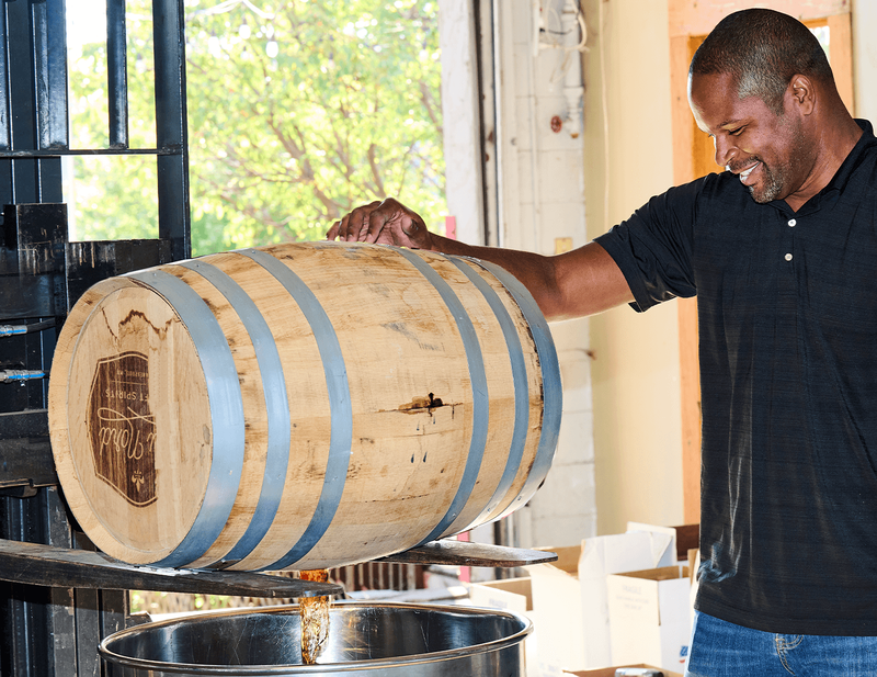 Chris Montana dumps a barrel of whiskey into a stainless steel vat to prepare it for bottling.